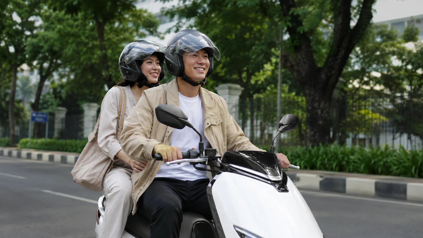 Pasangan Indonesia sedang naik motor listrik di jalan